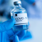 A hand in latex glove holding COVID19 vaccine bottle